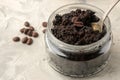 Homemade coffee face and body scrub in a glass jar with a spoon on a light background. care cosmetics