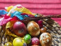 Homemade Colorful Painted easter eggs in straw flat basket with easter stickers and Pomlazka - czech traditional braided