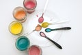 Homemade colorful paints for a baby. Glass jars with dough and food colorants and spoons on a white background.