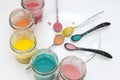 Homemade colorful paints for a baby. Glass jars with dough and food colorants and spoons on a white background.