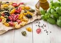 Homemade conchiglioni tricolore pasta in brown paper on white background with basil and oil. Black, red and green pasta