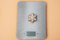 Homemade cookie. Bakery food art. Festive sweet ornament. Snowflake shaped gingerbread cookie on kitchen scales. Top view. Close- Royalty Free Stock Photo