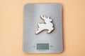 Homemade cookie. Bakery food art. Festive sweet ornament. White deer shaped gingerbread cookie on kitchen scales. Top view. Close- Royalty Free Stock Photo