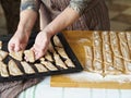 Homemade cookie concept. An elderly woman is hands place sliced raw biscuits on a baking sheet in the oven