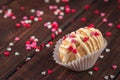 Homemade cookie shaped nuts with cream, chocolate icing on wooden table as a background, red, rose and white sugar sprinkle hearts Royalty Free Stock Photo
