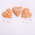Homemade cookies in the form of heart with letteing I Love You and sweets sugar candy hearts on the white background. Valentine da