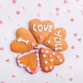 Homemade cookies in the shape of heart with letteing I Love You with sweets sugar candy hearts on the white background. Valentine