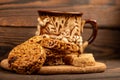 Homemade cookies with sunflower seeds and raisins, pieces of brown cane sugar and an earthenware mug of tea on a wooden table. Royalty Free Stock Photo