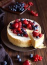 Homemade Creamy mascarpone cheesecake with berries forest fruits and strawberries on dark wooden table.