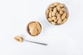 Homemade Creamy peanut butter or paste in spoon and raw unpeeled groundnut on white background. Delicious breakfast or snack