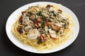 Homemade Creamy Tuscan Chicken with Pasta on a white plate on a black background, side view. Close-up Royalty Free Stock Photo