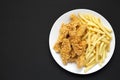 Homemade Crispy Chicken Tenders and French Fries on a white plate on a black background, top view. Copy space Royalty Free Stock Photo