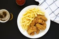 Homemade Crispy Chicken Wings and French Fries on a white plate on a black background, top view. From above, overhead, flat lay Royalty Free Stock Photo