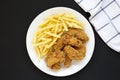 Homemade Crispy Chicken Wings and French Fries on a white plate on a black background, top view. From above, overhead, flat lay Royalty Free Stock Photo
