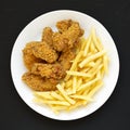 Homemade Crispy Chicken Wings and French Fries on a white plate on a black surface, top view. From above, overhead, flat lay Royalty Free Stock Photo