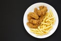 Homemade Crispy Chicken Wings and French Fries on a white plate on a black surface, top view. From above, overhead, flat lay. Copy Royalty Free Stock Photo