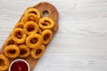 Homemade Crispy Deep-Fried Onion Rings with Ketchup on a rustic wooden board, top view. Flat lay. Space for text Royalty Free Stock Photo