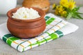 Homemade crumbly farmer\'s cheese in a clay pot. Wooden background.