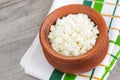 Homemade crumbly farmer\'s cheese in a clay pot. Wooden background. Copy space, top view