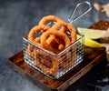 Homemade crunchy fried onion rings in deep fryer dish with lime top view on dark background