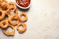 Homemade crunchy fried onion rings and tomato sauce on light background, top view. Royalty Free Stock Photo