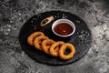 Homemade crunchy fried onion rings with tomato sauce on stone board, american unhealthy calories meal. Delicious pub style, Royalty Free Stock Photo