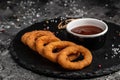 Homemade crunchy fried onion rings with tomato sauce on stone board, american unhealthy calories meal. Delicious pub style, Royalty Free Stock Photo