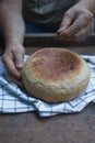 Homemade crusty loave of bread on wooden background. Baker holding fresh bread in the hands. view from above. Dark mood