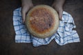 Homemade crusty loave of bread on wooden background. Baker holding fresh bread in the hands. view from above. Dark mood