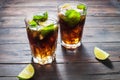 Homemade Cuba Libre with fresh lime, brown rum and crushed ice on an old wooden table Royalty Free Stock Photo