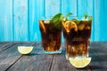 Homemade Cuba Libre with fresh lime, brown rum and crushed ice on an old wooden table Royalty Free Stock Photo