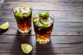 Homemade Cuba Libre with fresh lime, brown rum and crushed ice on an old wooden table Royalty Free Stock Photo