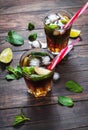 Homemade Cuba Libre with fresh lime, brown rum and crushed ice on an old wooden table Royalty Free Stock Photo