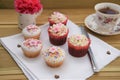 Homemade cup cakes with iced pink flower decorations and cup of tea Royalty Free Stock Photo