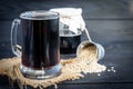 Homemade dark beer in bottles and a glass on a dark background. Nearby are barley grains and ears of wheat. Dark background Royalty Free Stock Photo