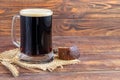 Homemade dark beer in bottles and a glass on a dark background. Nearby are barley grains and ears of wheat. Dark background Royalty Free Stock Photo