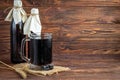 Homemade dark beer in bottles and a glass on a dark background. Nearby are barley grains and ears of wheat. Dark background Royalty Free Stock Photo