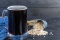 Homemade dark beer in bottles and a glass on a dark background. Nearby are barley grains and ears of wheat. Dark background Royalty Free Stock Photo