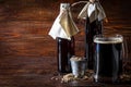 Homemade dark beer in bottles and a glass on a dark background. Nearby are barley grains and ears of wheat. Dark background Royalty Free Stock Photo