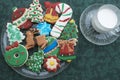 Homemade Decorated Cutout Christmas Cookies On Clear Plate,Green Tablecloth, Glass of Milk