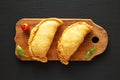 Homemade Deep Fried Italian Panzerotti Calzone on a rustic wooden board on a black background, top view. Flat lay, overhead, from Royalty Free Stock Photo