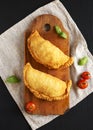 Homemade Deep Fried Italian Panzerotti Calzone on a rustic wooden board on a black surface, overhead view. From above, top view. Royalty Free Stock Photo