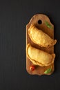Homemade Deep Fried Italian Panzerotti Calzone on a rustic wooden board on a black surface, top view. Flat lay, overhead, from Royalty Free Stock Photo