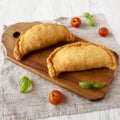 Homemade Deep Fried Italian Panzerotti Calzone on a rustic wooden board on a white wooden background, low angle view. Close-up Royalty Free Stock Photo