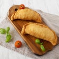 Homemade Deep Fried Italian Panzerotti Calzone on a rustic wooden board on a white wooden table, side view Royalty Free Stock Photo