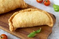 Homemade Deep Fried Italian Panzerotti Calzone on a rustic wooden board on a white wooden table, side view. Close-up Royalty Free Stock Photo