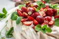 Homemade delicious meringue cake Pavlova with whipped cream, fresh strawberrie and mint. Food recipe background. Close up