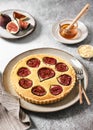 Homemade delicious tart with figs on a plate. Roast almond nuts and honey for decoration.
