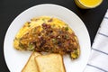 Homemade Denver Omelette on a white plate on a black background, top view. Flat lay, overhead, from above