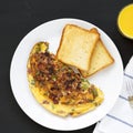 Homemade Denver Omelette on a white plate on a black background, top view. Flat lay, overhead, from above